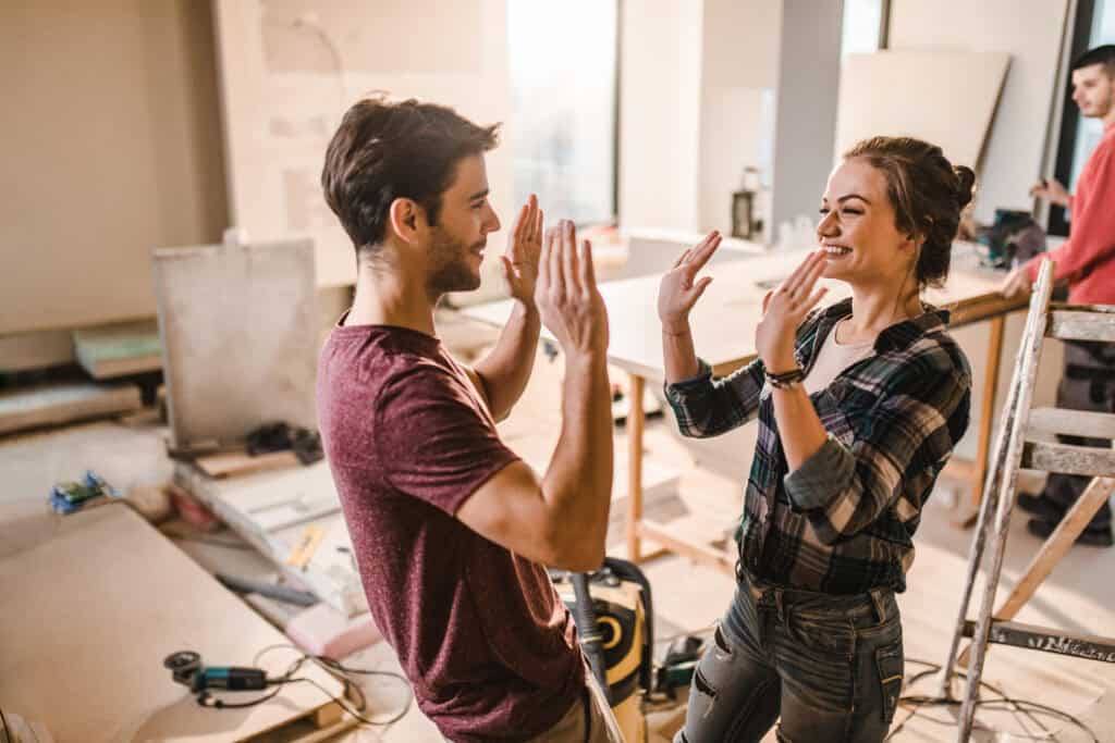 Lachend stel geeft elkaar een high five tijdens hun verbouwing thuis