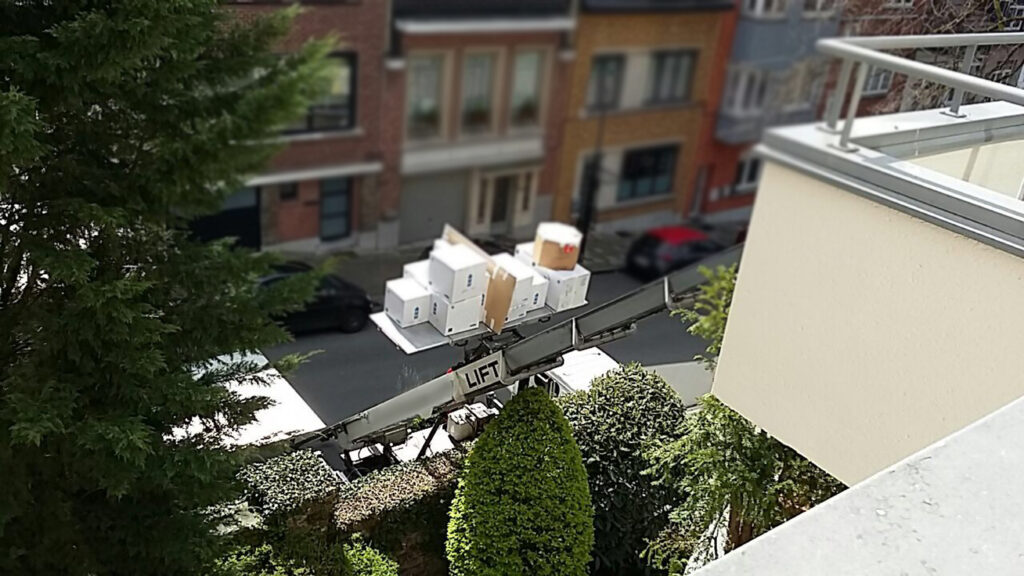 Verhuisdozen worden met een verhuislift omhooggebracht in een smalle stadsstraat