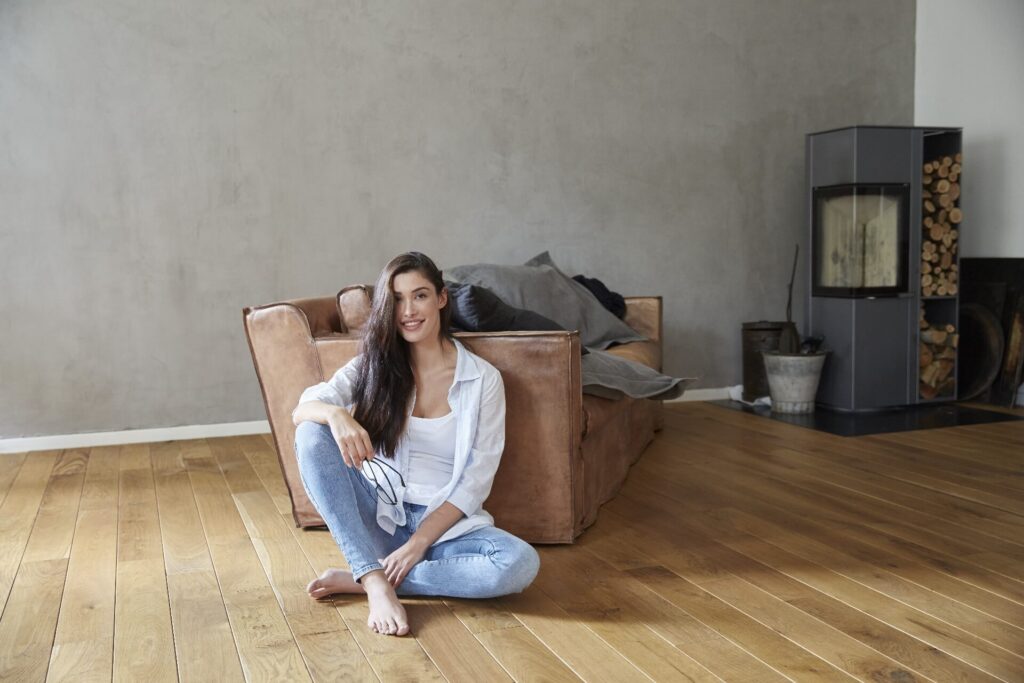 Vrouw op blote voeten op houten vloer in warme woonkamer zonder vloerkleed