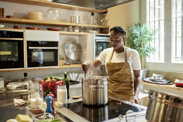Vrouw kookt op een inductiekookplaat in een moderne keuken met verse ingrediënten