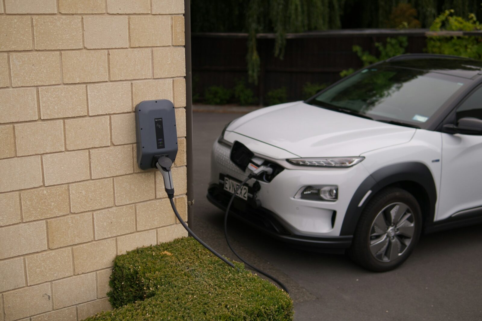 Elektrische auto aan laadpaal bij woning met oprit