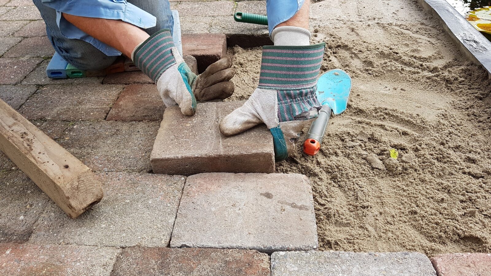Close-up van bestrating in voortuin met werkhandschoenen en klinkers