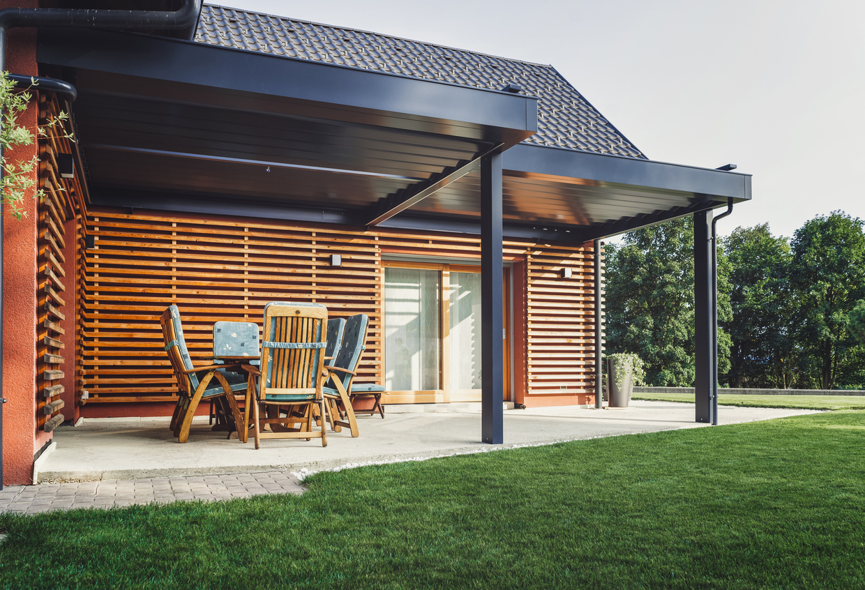 Modern huis met houten zonwering op de gevel en terrasoverkapping in de zon