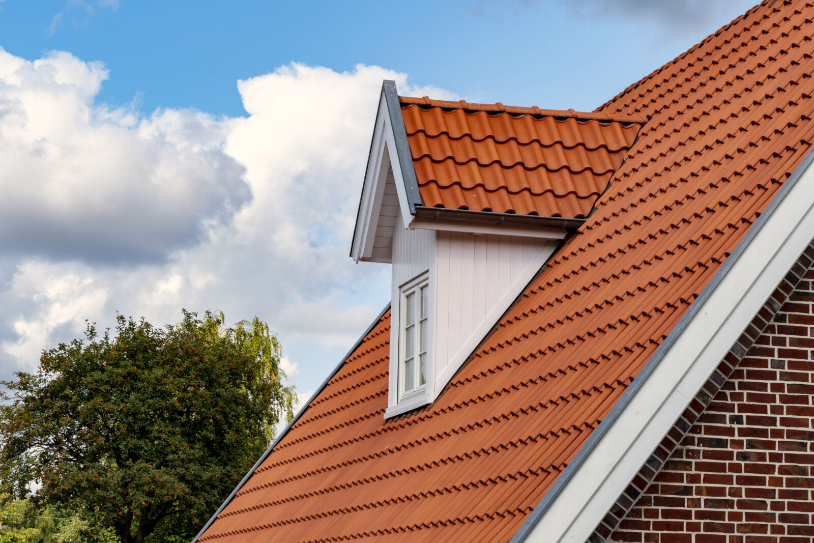 Modern keramisch pannendak met witte dakkapel op een traditionele woning