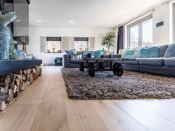 Lichte woonkamer met houtlook PVC vloer, natuurlijk licht en warme inrichting