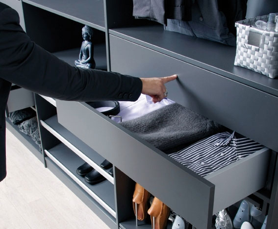 Donkere modulaire kledingkast met uitschuifbare lade vol netjes gevouwen kleding