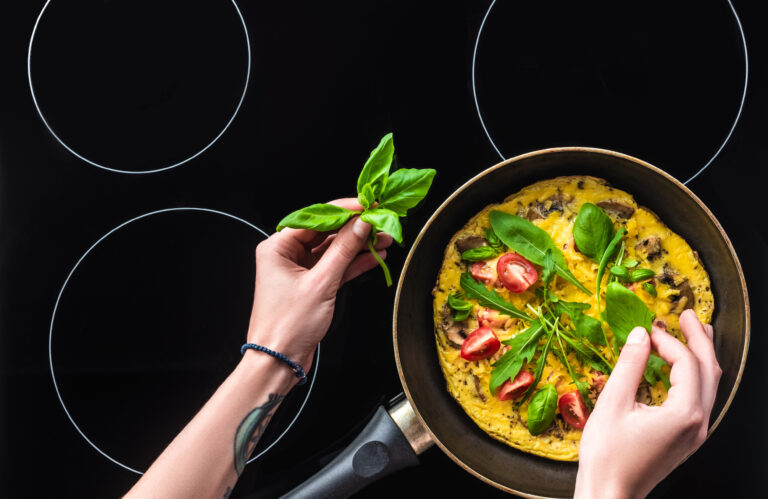 Bovenaanzicht van een koekenpan met verse groenten op een glanzende inductiekookplaat