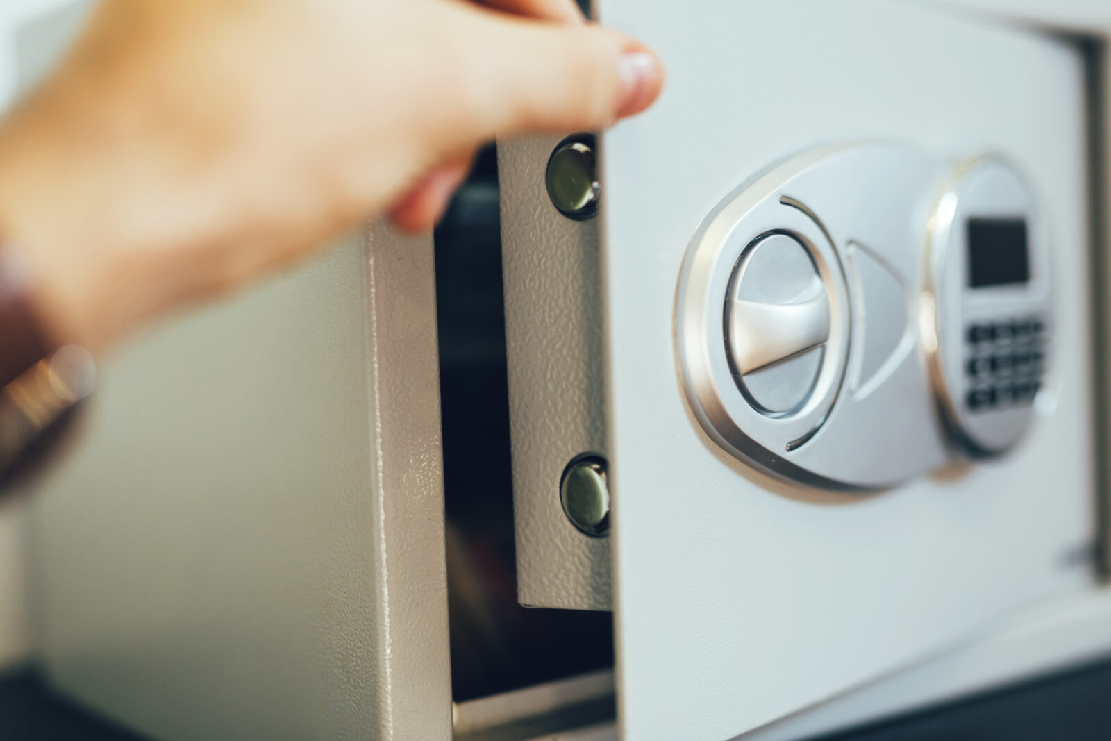 Hand opent een kluisdeur om waardevolle spullen veilig op te bergen in huis