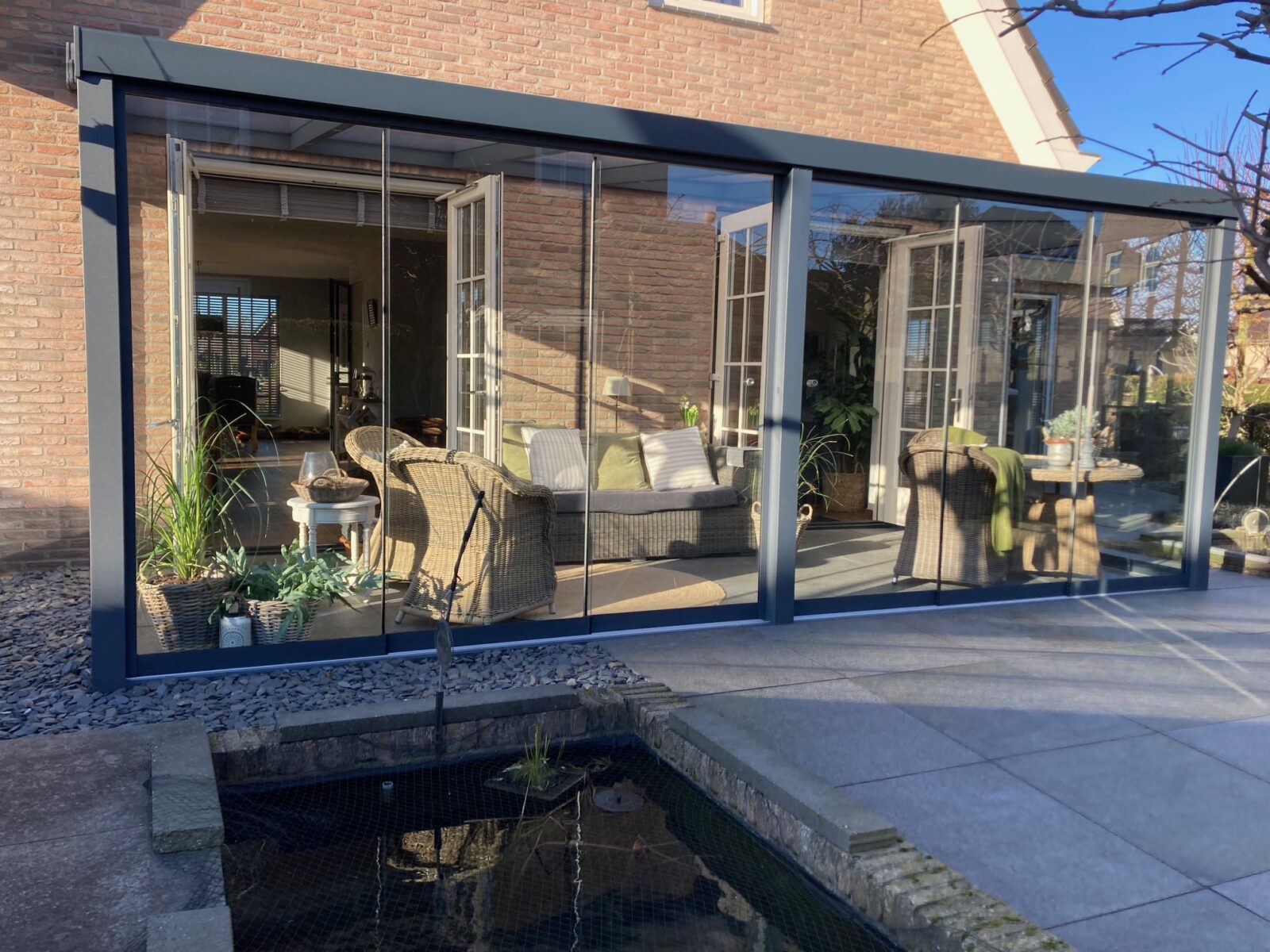 Moderne veranda met glazen schuifwanden die woonkamer en tuin naadloos verbinden
