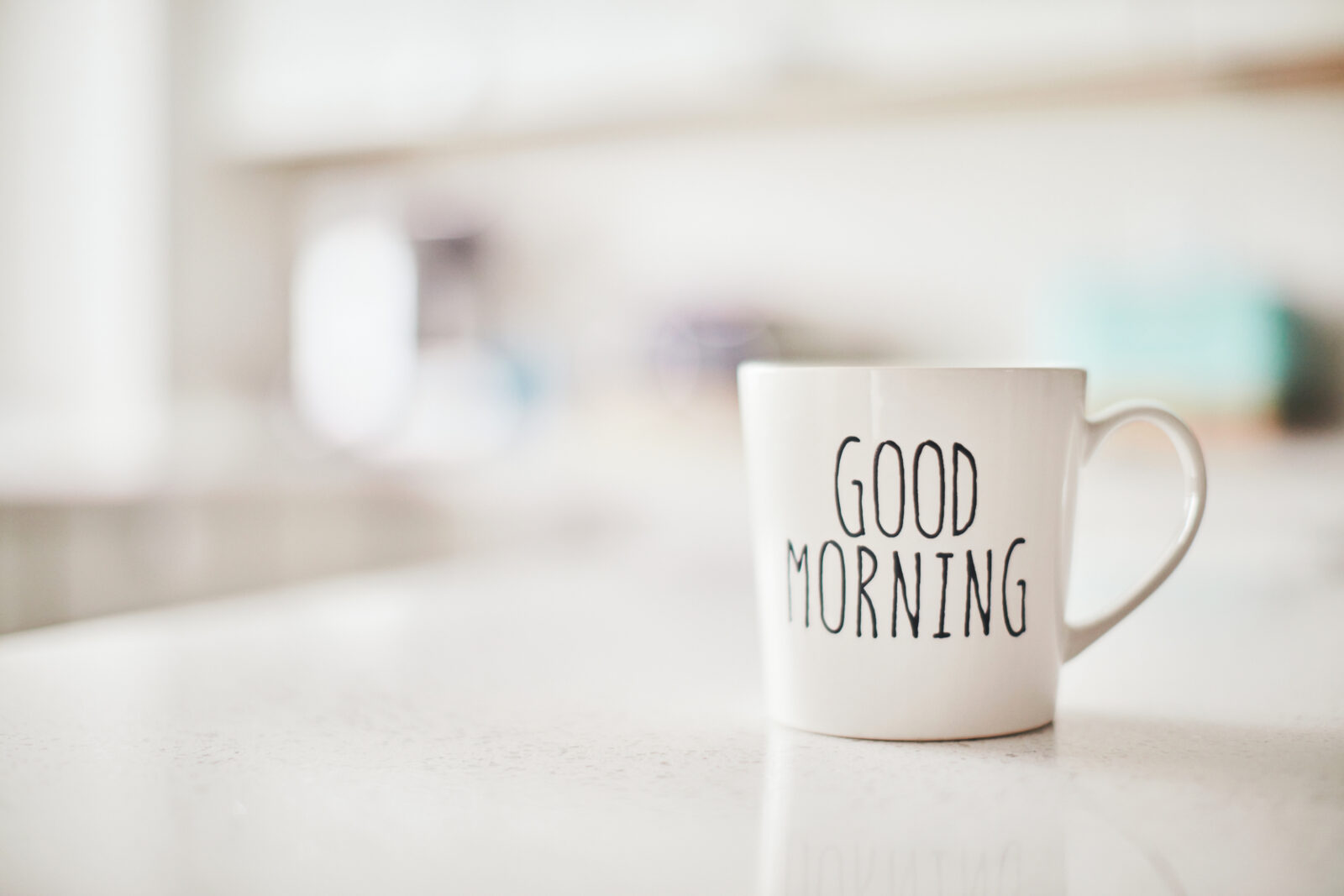 Witte mok met de tekst Good Morning op een lichte keukentafel.