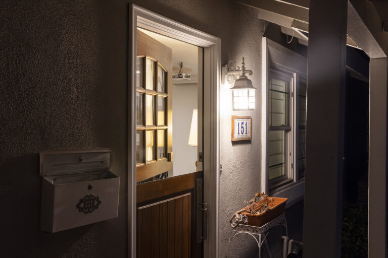 Buitenlamp verlicht een openstaande voordeur in de avond