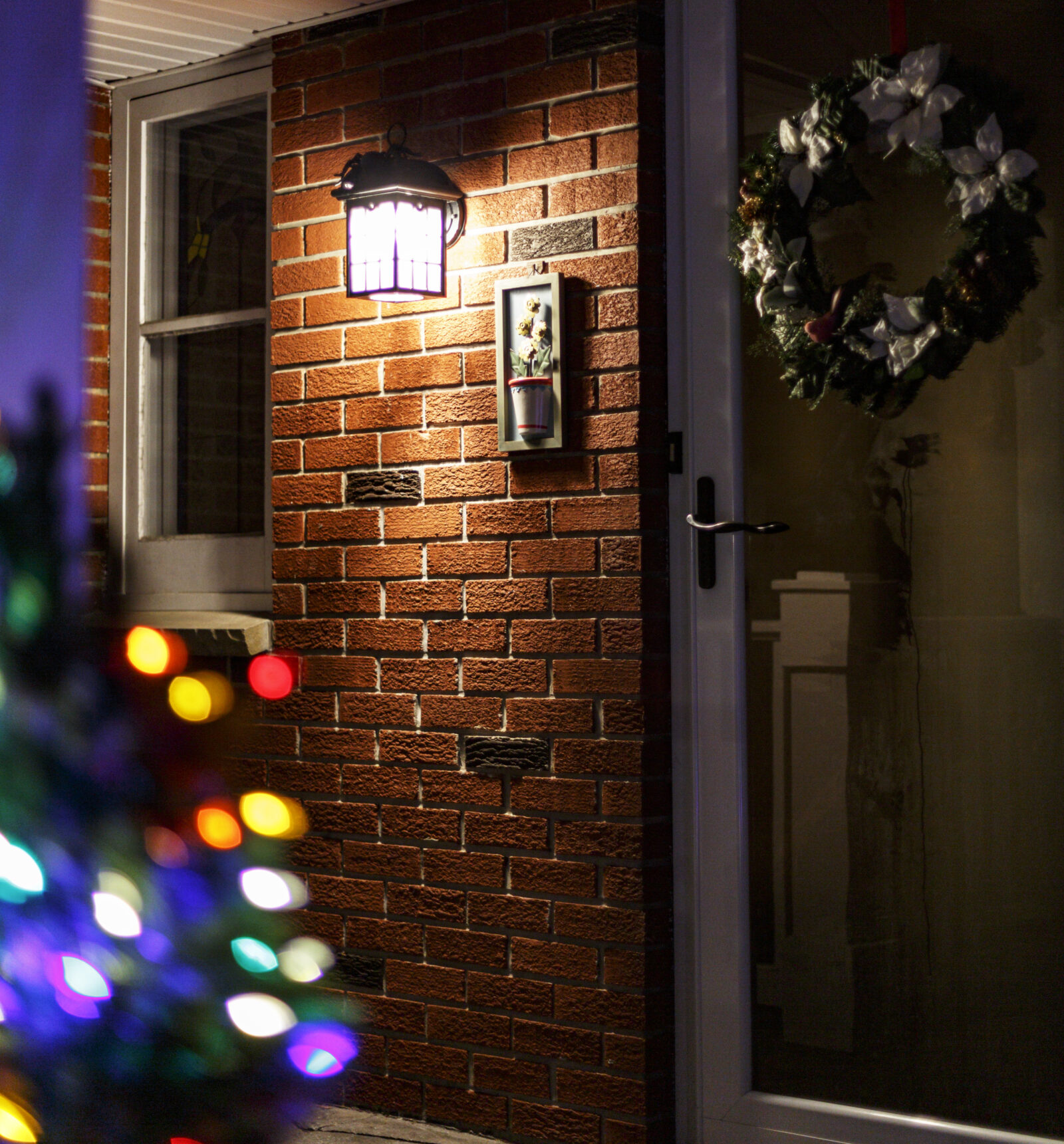 Wandlamp verlicht een voordeur met winterse decoratie