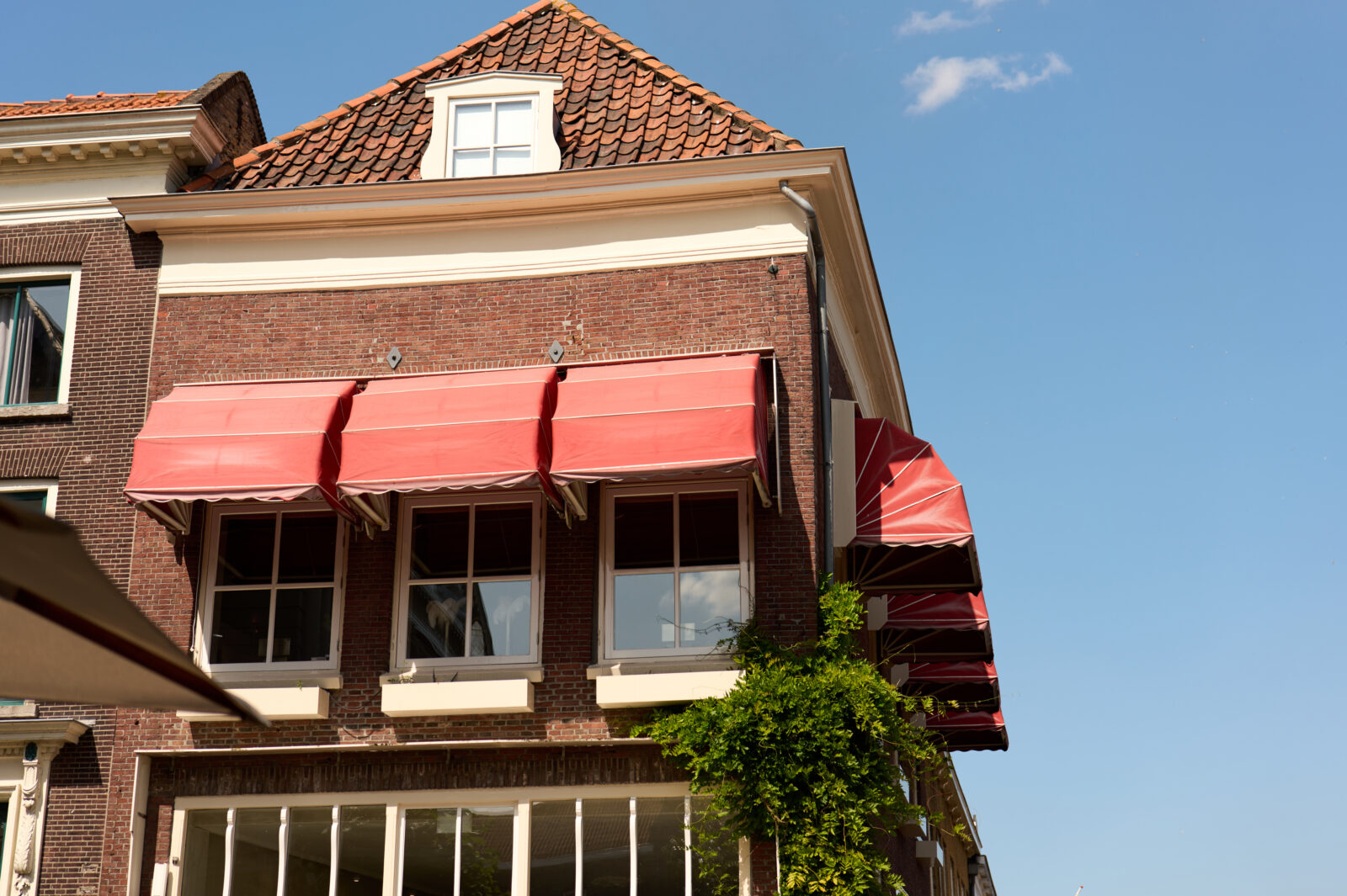 Historische Nederlandse huizen met markiezen die houten kozijnen beschermen tegen zonlicht