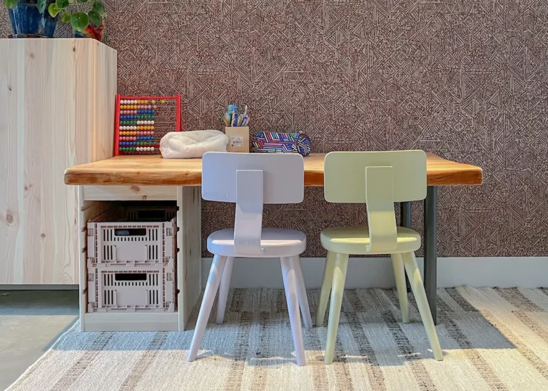 Slim ingerichte speelhoek met houten bureau, twee kinderstoeltjes en handige opbergbakken – ontwerp van Bente Metselaar