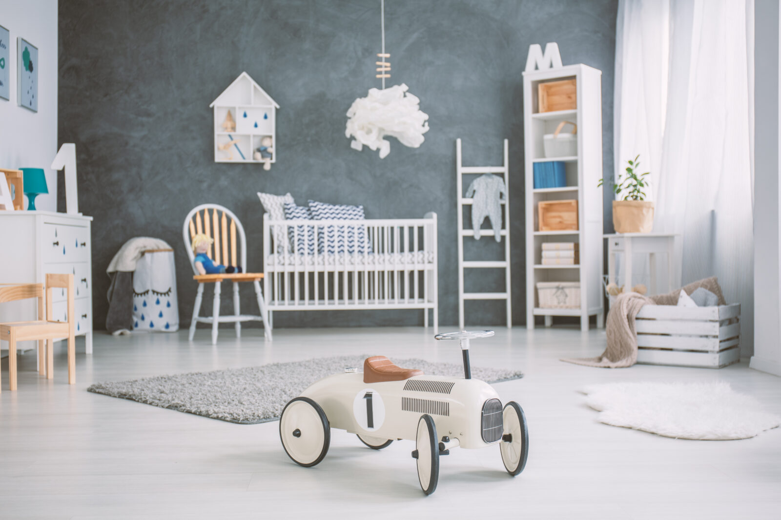 Stijlvolle babykamer met wit ledikant, houten accenten en speelgoedauto op zachte vloer.
