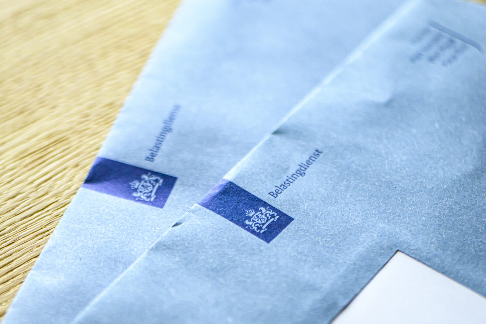 Twee blauwe enveloppen van de Belastingdienst liggen op tafel, symbool voor belastingzaken rond de eigen woning