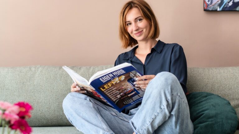 Bente Metselaar leest op de bank een woonmagazine in een kleurrijk en comfortabel interieur