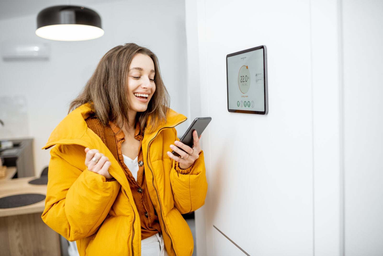 Vrouw bedient slimme thermostaat met haar smartphone om energie te besparen