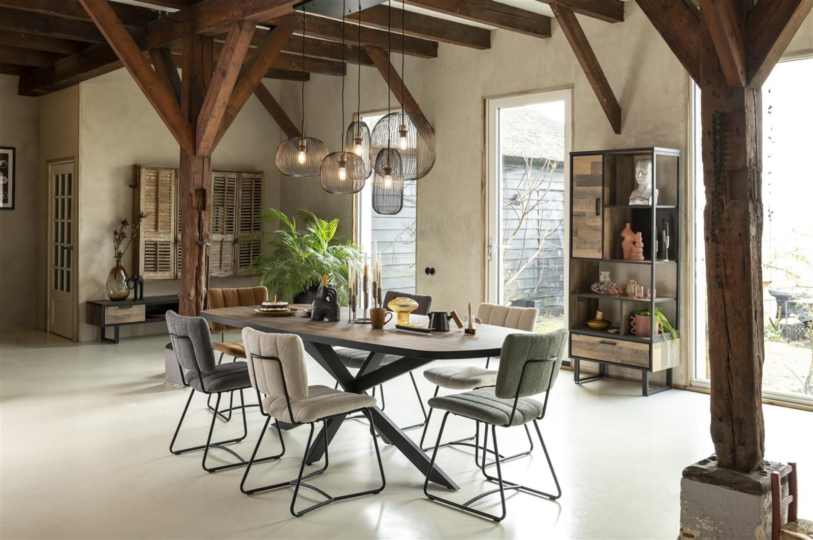 Eetkamer met stoelen in verschillende kleuren en materialen rond een houten tafel
