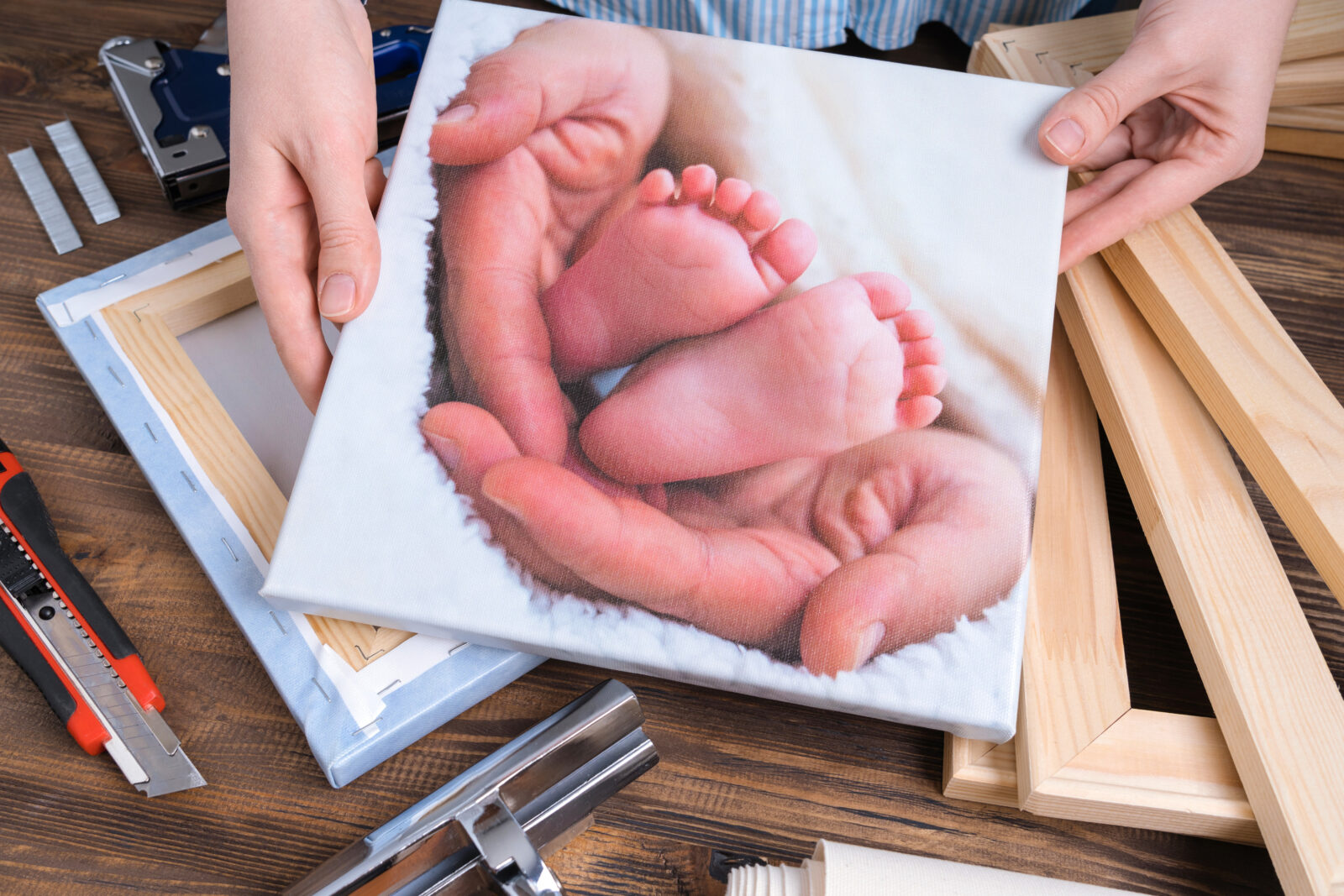 Handen houden een canvas vast met een foto van babyvoetjes – een warm en persoonlijk detail voor in huis.