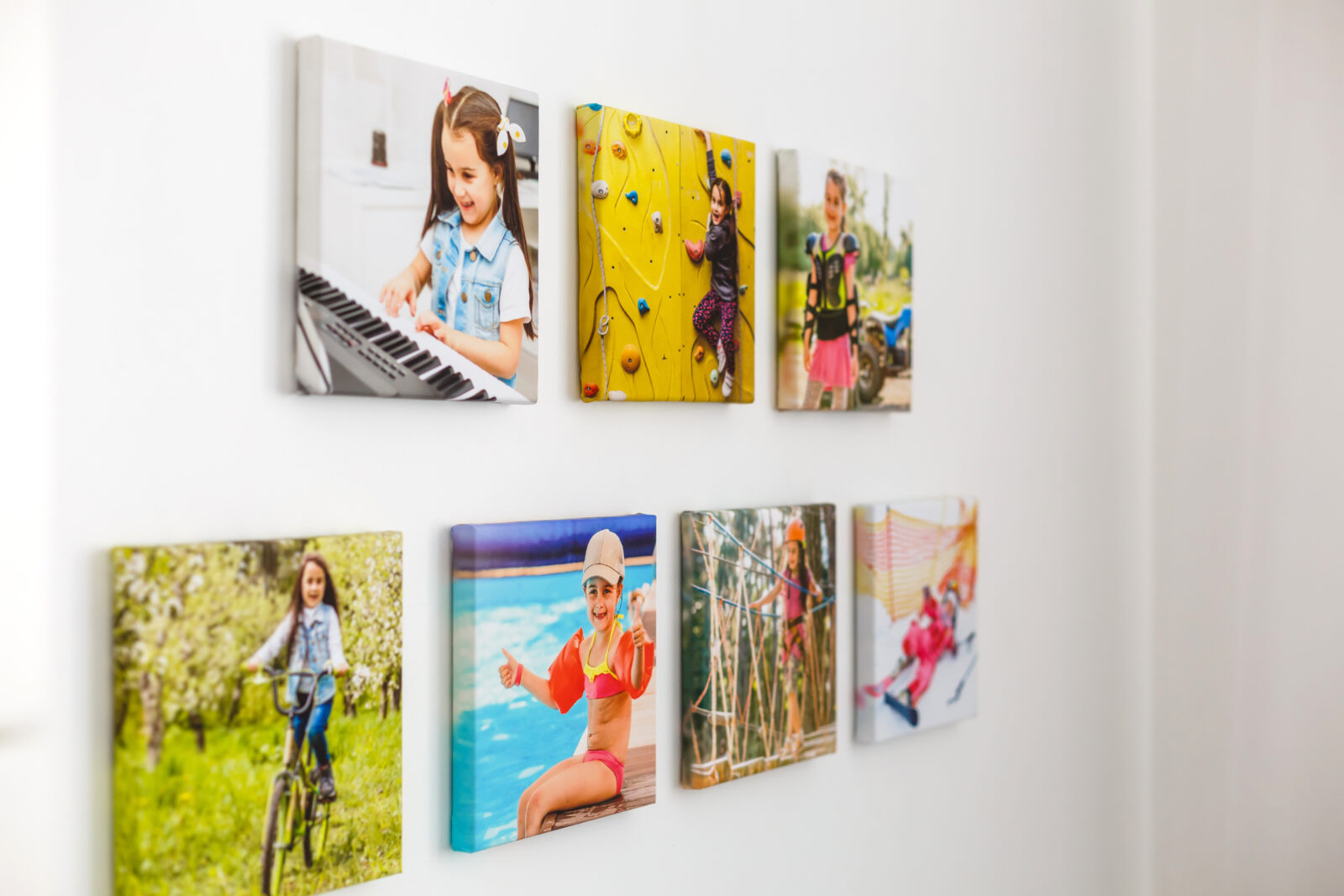 Kleurrijke familie­foto’s op canvas aan een witte muur, badend in zacht daglicht in een modern interieur.