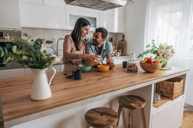 Gezellig stel dat samen kookt in een lichte keuken met houten werkblad en betaalbare, stijlvolle uitstraling