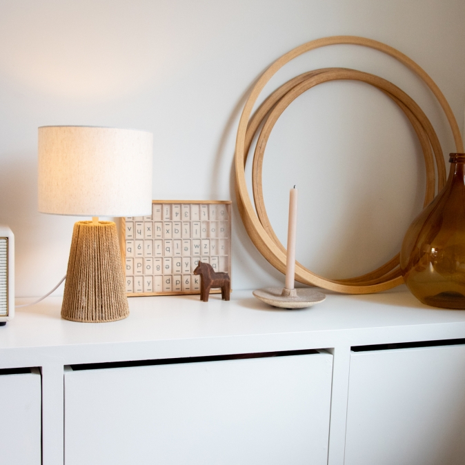 Natuurlijke tafellamp van touw op wit dressoir met houten en glazen decoraties