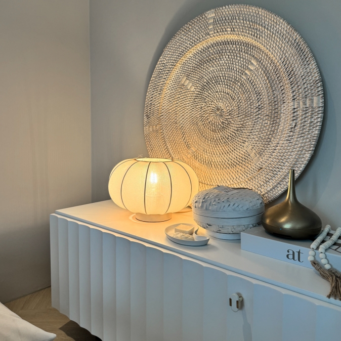 Sfeervolle tafellamp met zacht licht op wit dressoir, gecombineerd met decoratieve accessoires