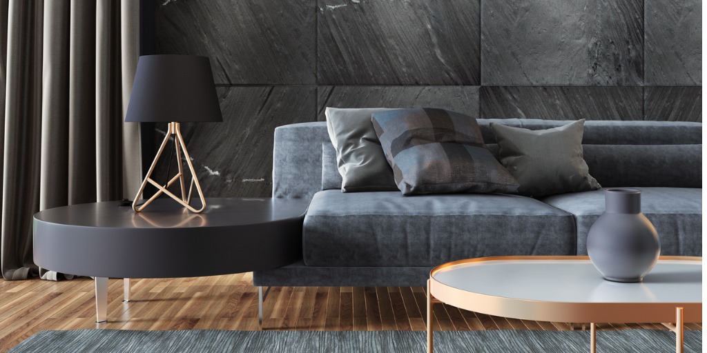 Moderne woonkamer met donkere ronde salontafels, grijze bank en koperkleurige accenten.