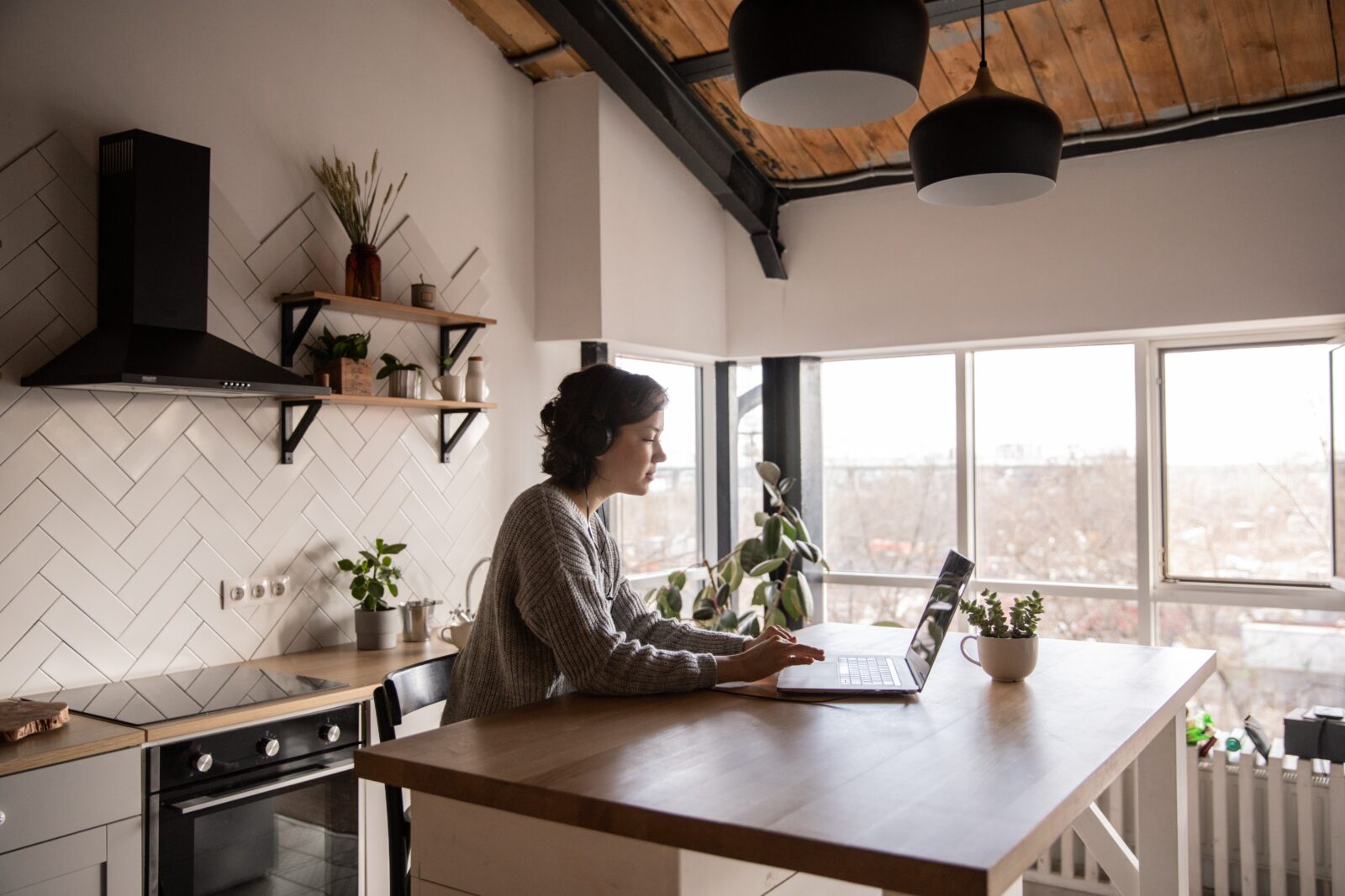 Vrouw werkt op een laptop aan het houten werkblad van een compacte, lichte keuken