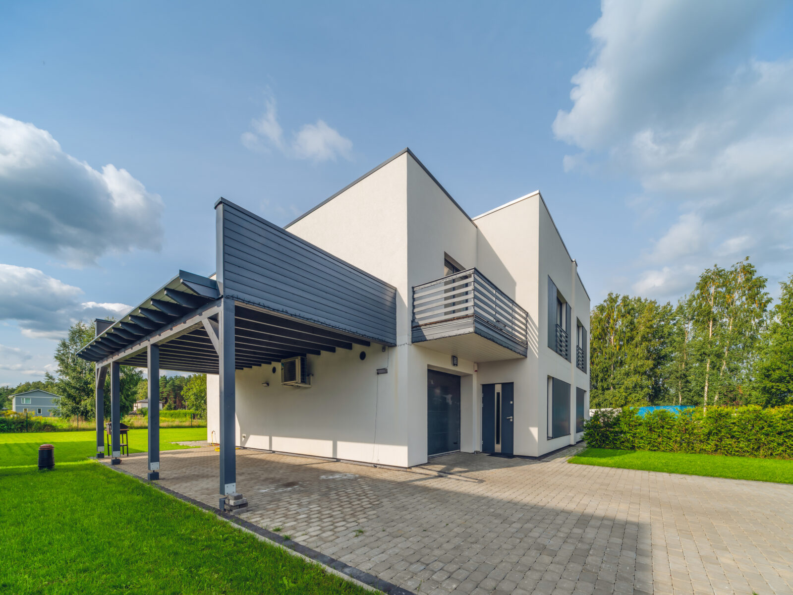 Moderne woning met aluminium carport en oprit onder blauwe lucht