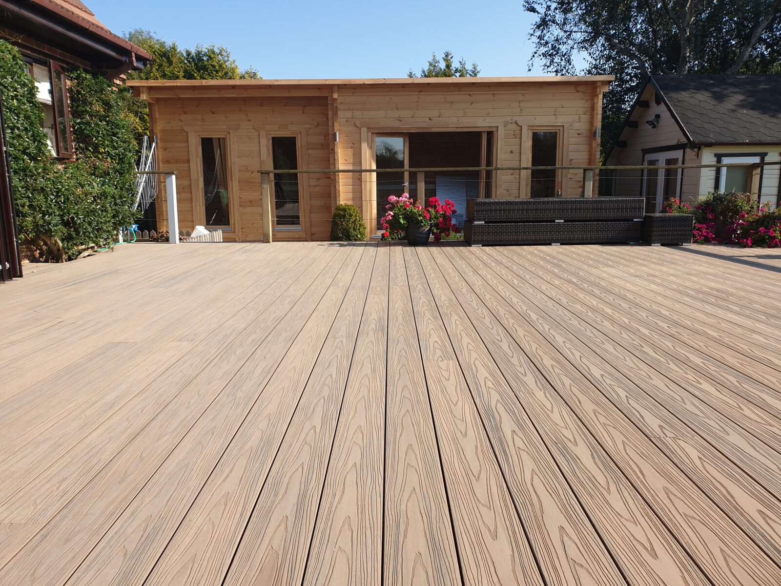Composiet vlonderplanken met houtnerfstructuur op ruim terras bij tuinhuis