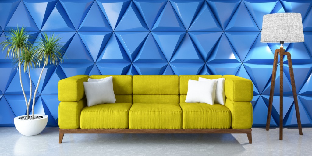 Gele designbank voor felblauwe geometrische wand met opvallende vloerlamp en groene kamerplant