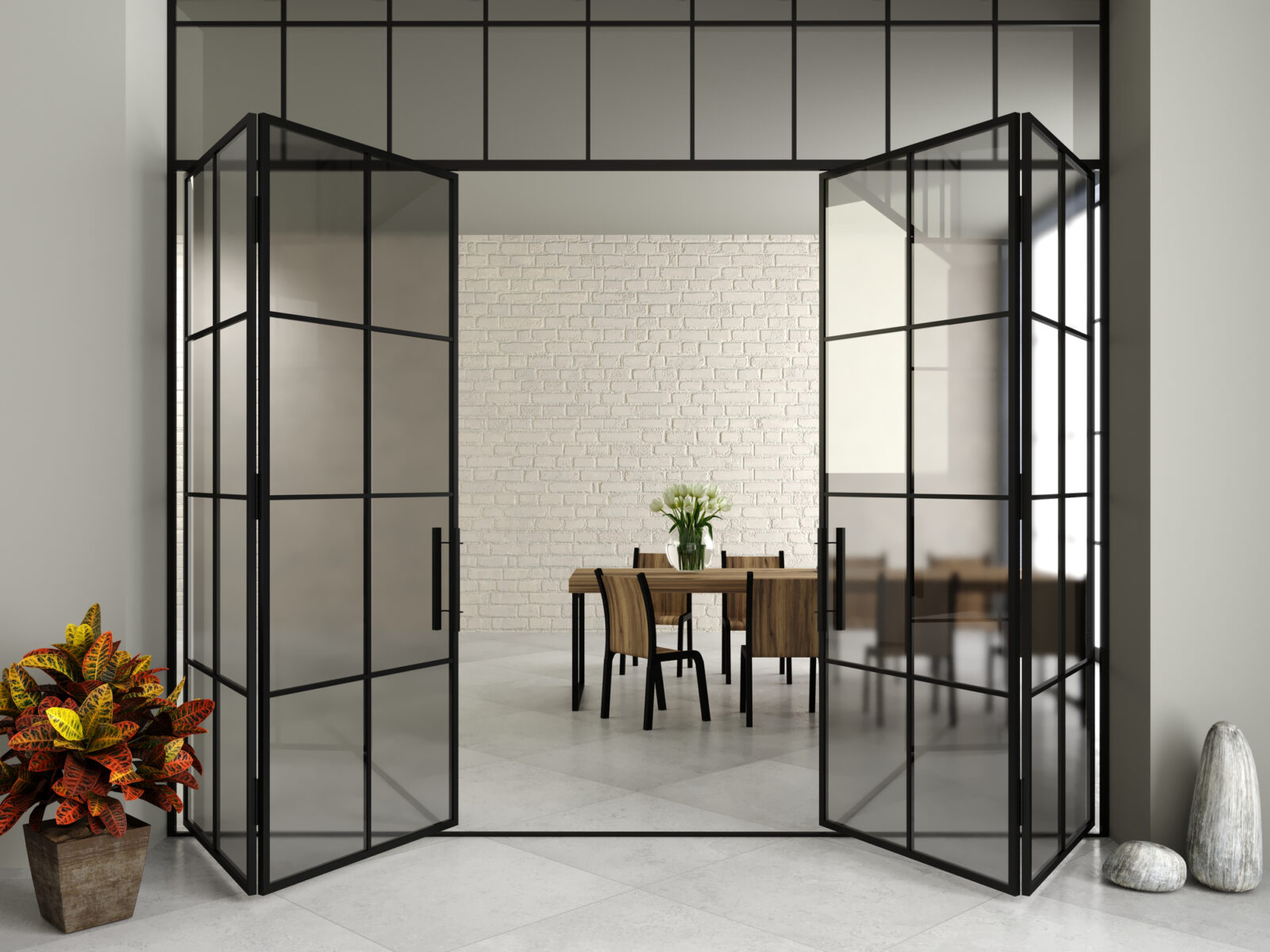 Zwarte stalen binnendeuren die openen naar een lichte eetkamer met houten tafel en neutrale tinten.