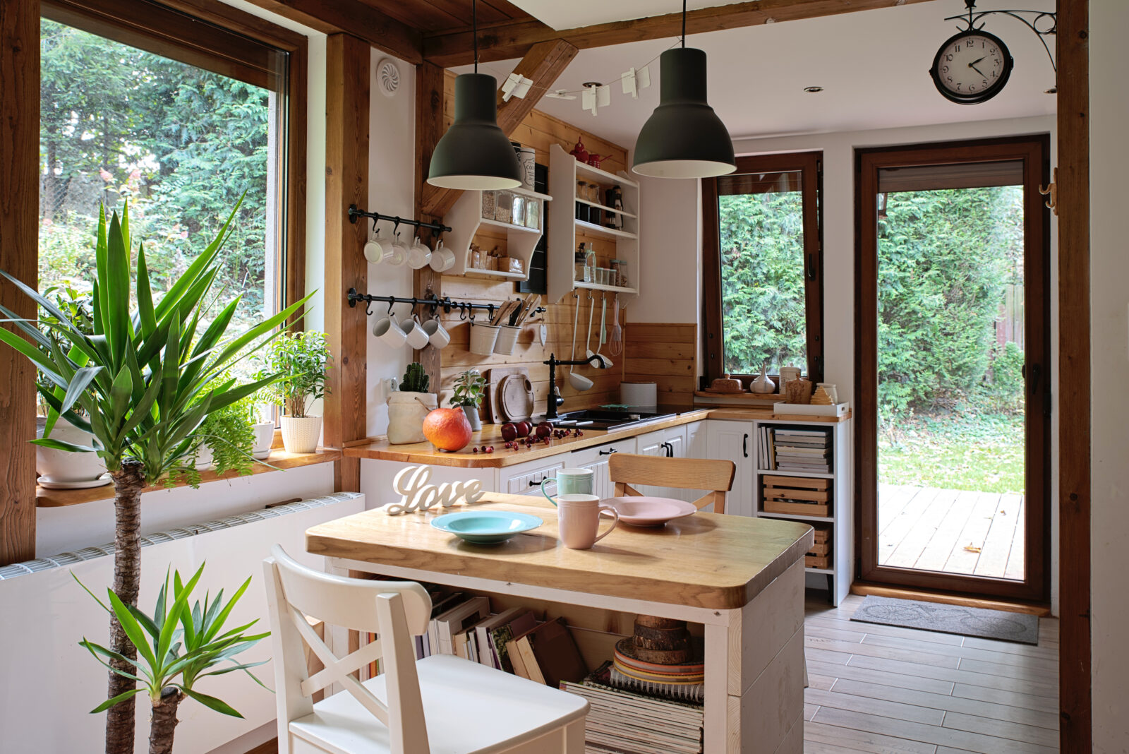 Compacte houten keuken met veel daglicht en openslaande deuren naar buiten.