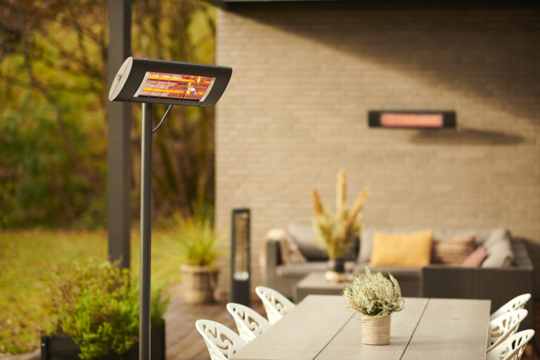 Infrarood terrasheater die een warm licht geeft op een sfeervol ingericht buitenzitje in de tuin.