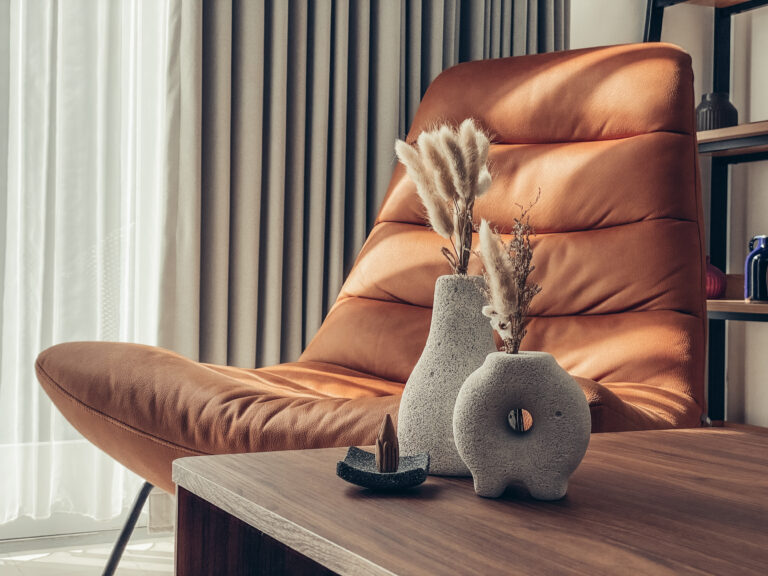 Keramieken landelijke vazen met gedroogde takken op een houten tafel in een warme, natuurlijke woonkamer.