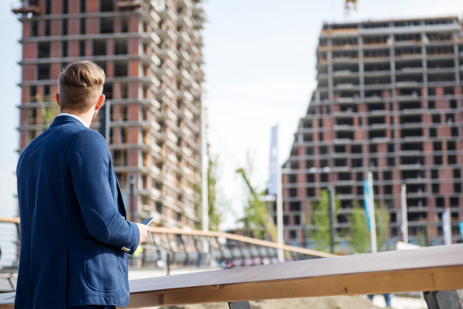 Investeerder kijkt vanaf de bouwplaats naar twee nieuwe woongebouwen in aanbouw.