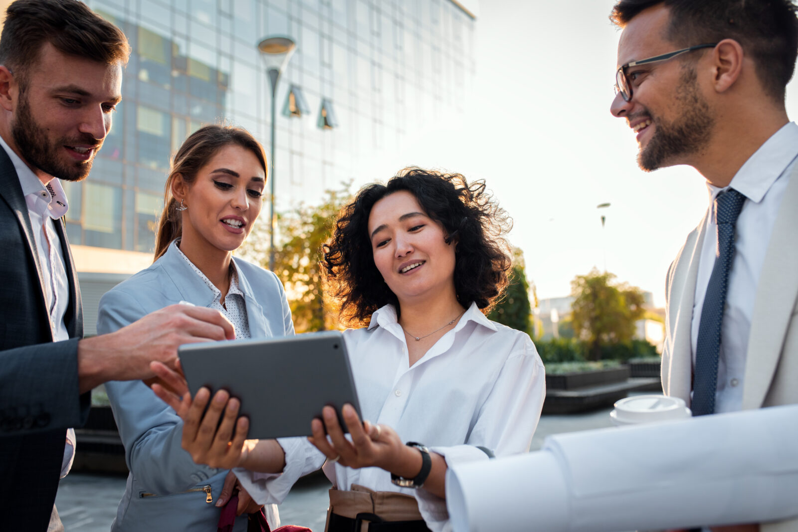 Professionals bekijken samen vastgoedinformatie op een tablet voor een modern kantoorgebouw.