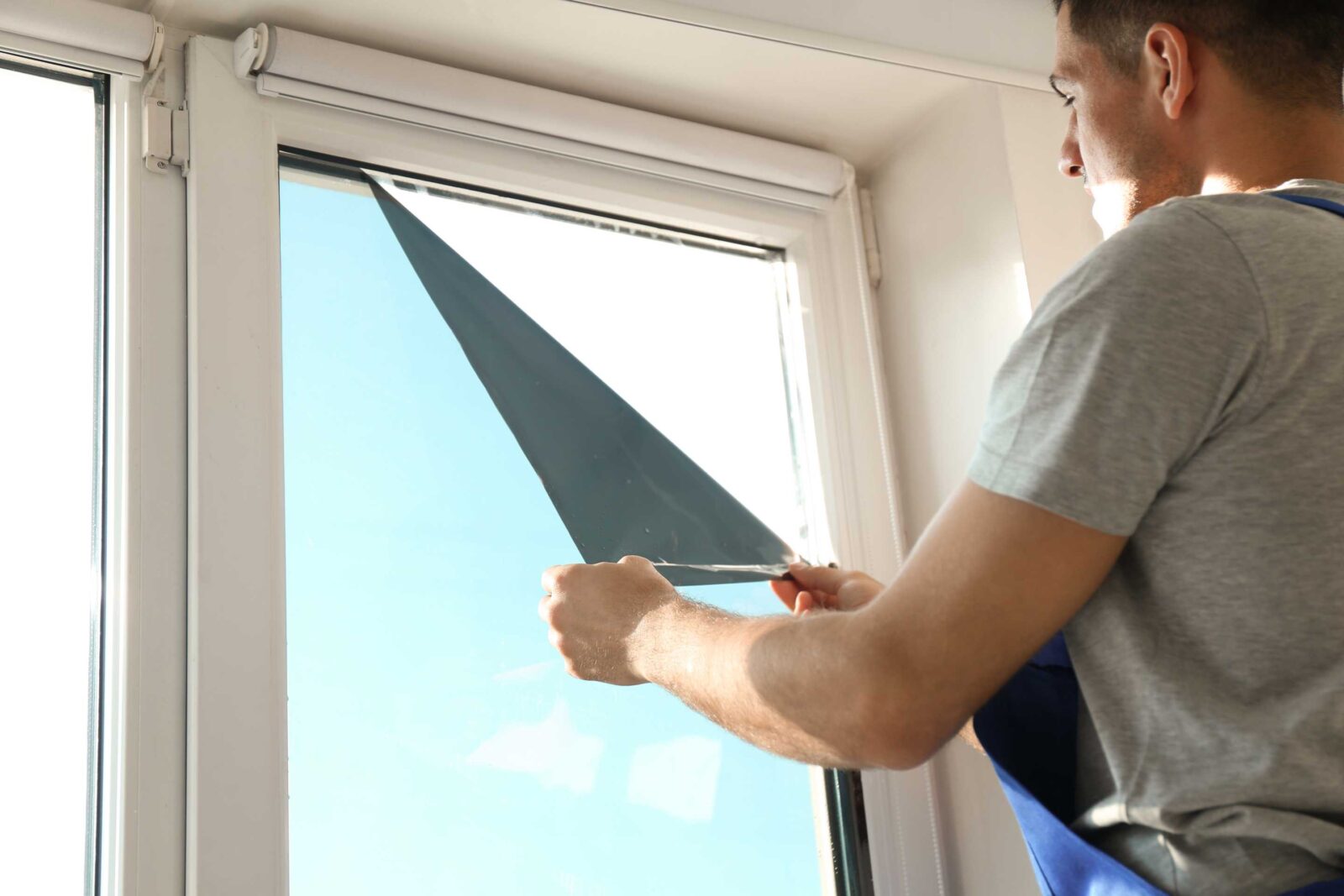 Man brengt spiegelfolie aan op een raam om privacy en veiligheid in huis te vergroten.