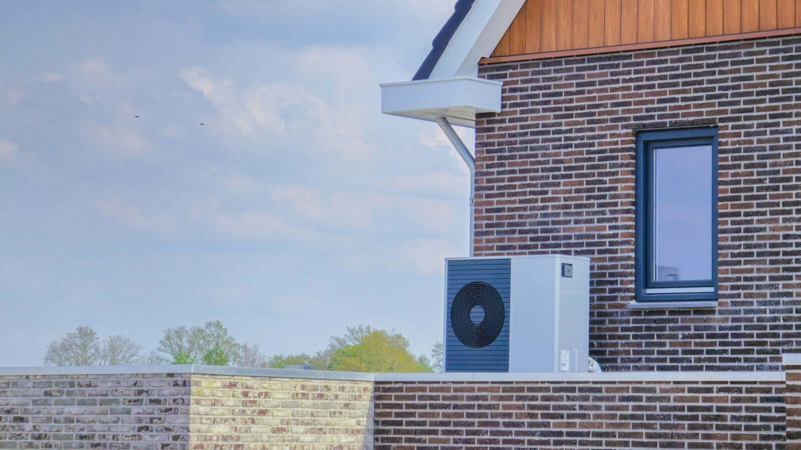 Warmtepomp buitenunit geplaatst tegen een gevel in een woonwijk