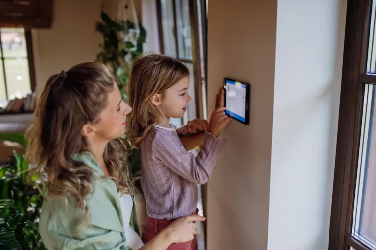 Moeder en kind die samen de slimme thermostaat instellen in een warme, huiselijke woonkamer.
