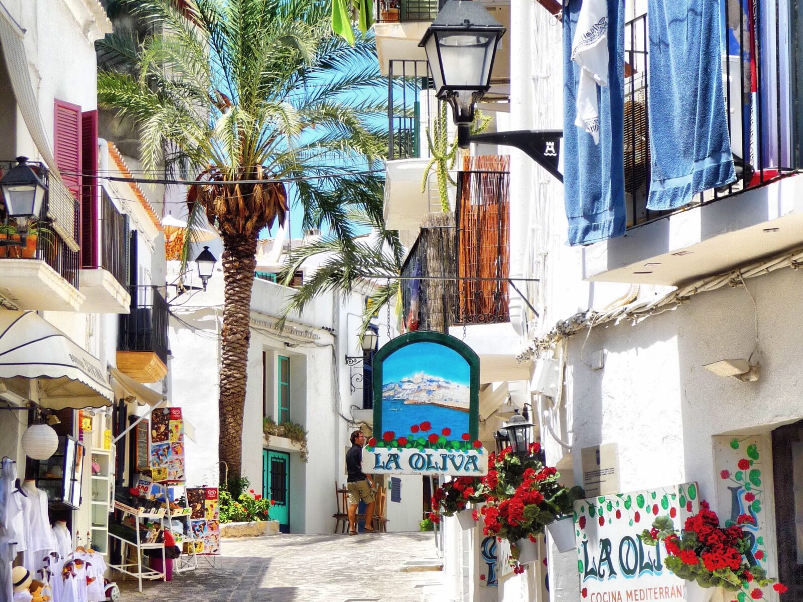 Kleurrijke straat in Ibiza met palmbomen, witte huizen en mediterrane sfeer op een zonnige dag