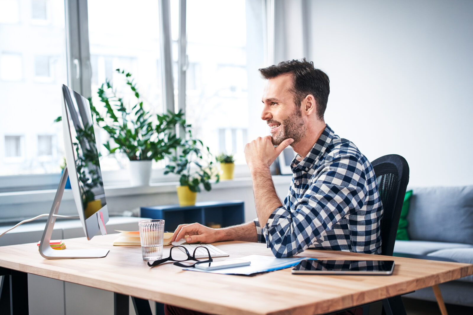 Man die geconcentreerd werkt aan een bureau met veel daglicht en planten om zich heen.
