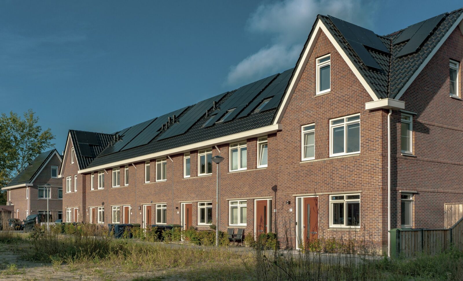 Nieuwbouwwoningen met zonnepanelen in een Nederlandse woonwijk bij helder weer.