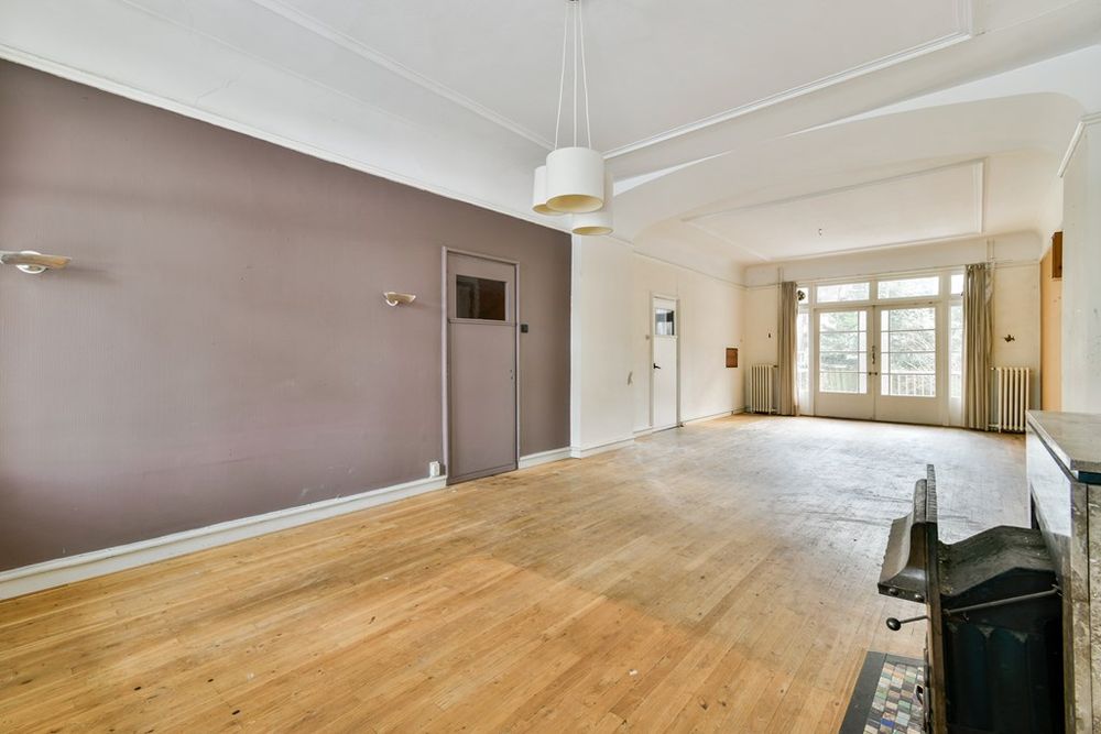 Lege woonkamer met houten vloer en openslaande deuren aan de Apollolaan in Amsterdam