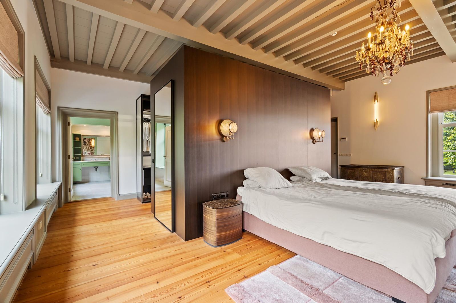 Slaapkamer van Lindenhof in Noordwijk met houten balkenplafond, maatwerk wand en zicht op de badkamer