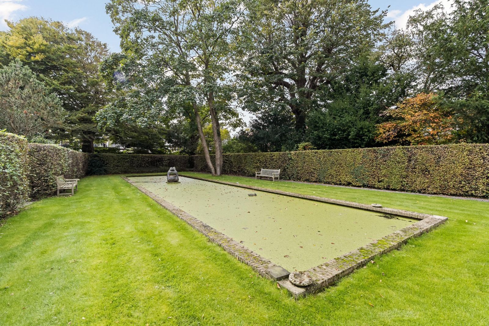 Formele tuin van Lindenhof in Noordwijk met rechthoekige vijver, hagen en volwassen bomen