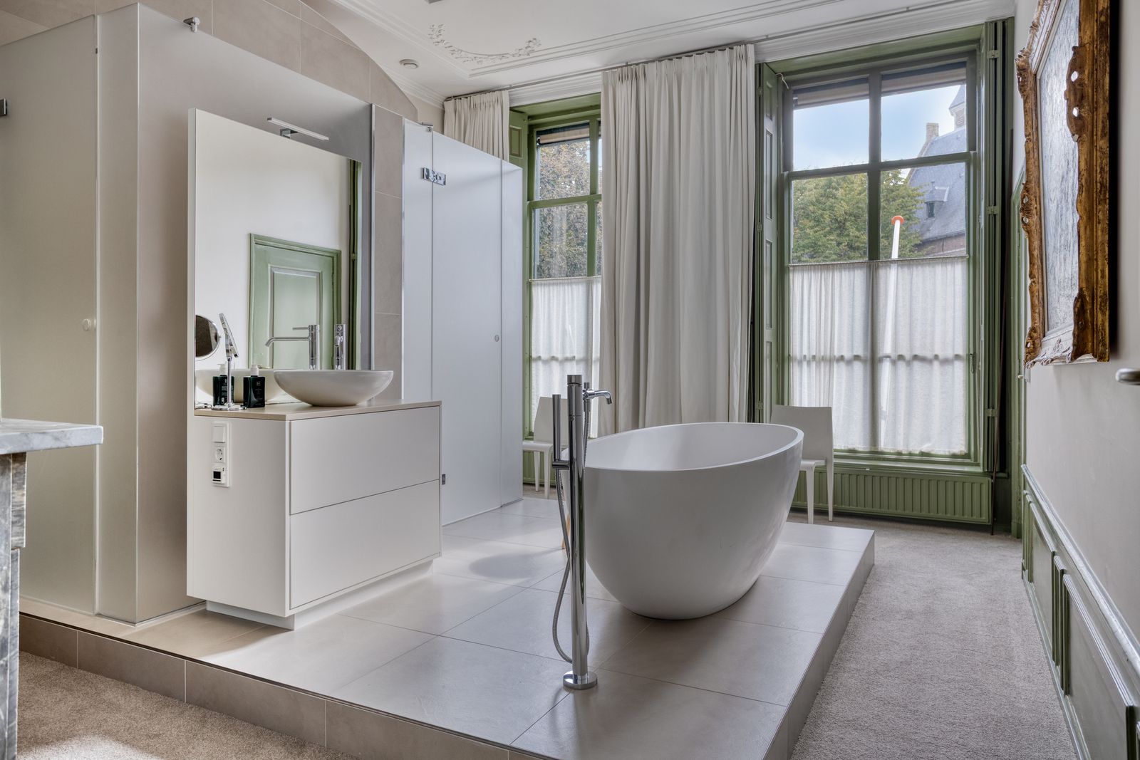 Badkamer met vrijstaand bad en hoge ramen in monumentaal huis in Middelburg