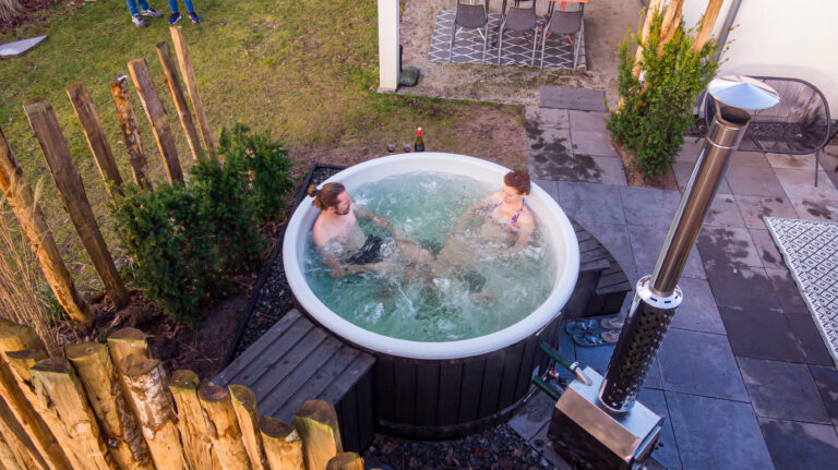 Koppel ontspant in een houtgestookte hottub in een moderne achtertuin